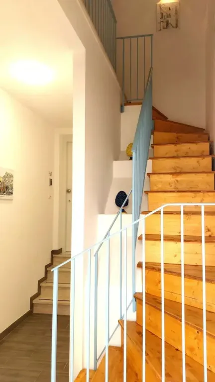 Scala interna in legno con ringhiera bianca e corridoio