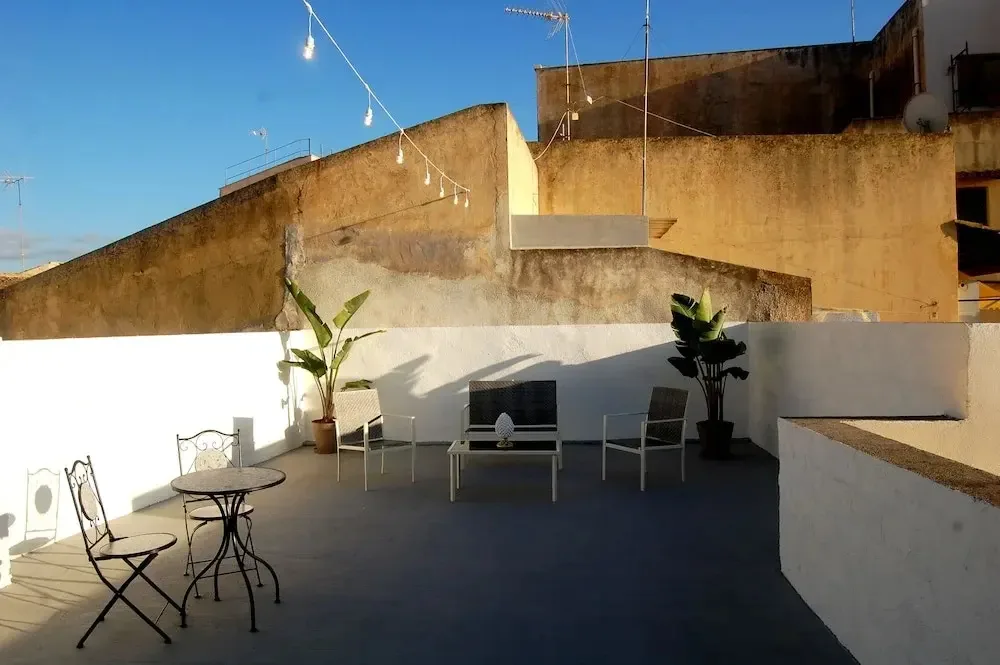 Terrazza esterna con tavolini, sedie e piante sotto il cielo azzurro