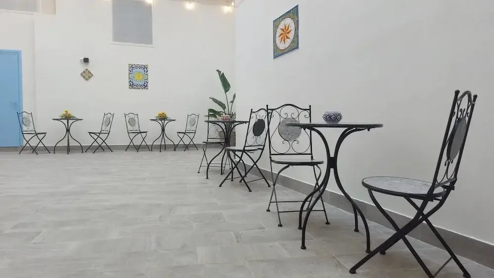 Sala comune con tavolini in ferro battuto, sedie e decorazioni in ceramica