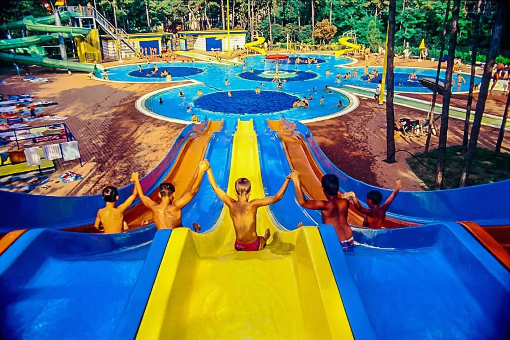 Bambini che scendono dagli scivoli acquatici verso le piscine del parco