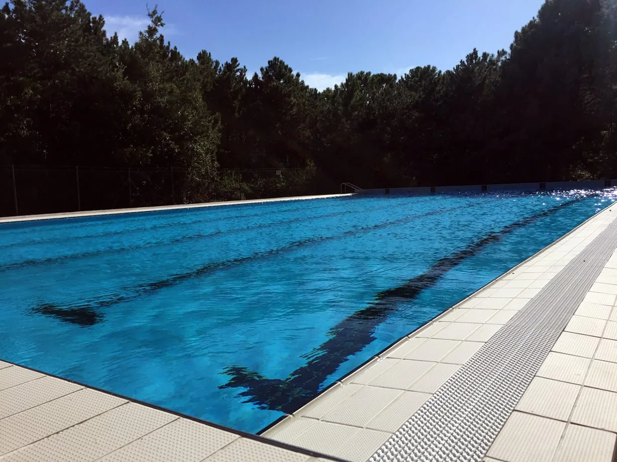 Piscina olimpionica esterna con corsie immersa nel verde