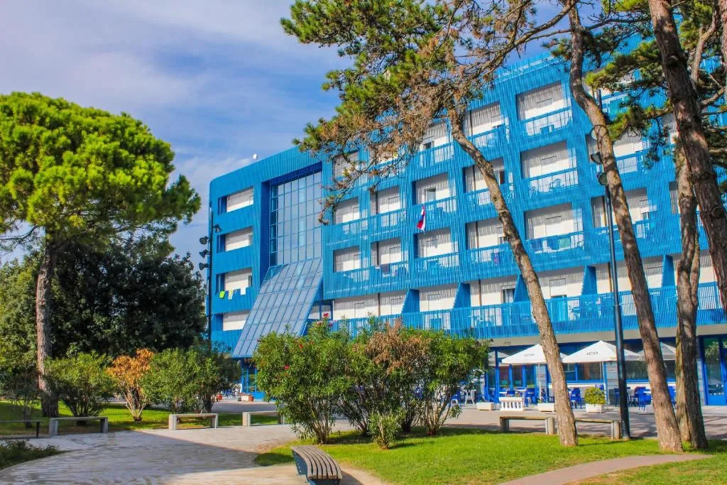 Edificio blu con balconi circondato dal verde e alberi
