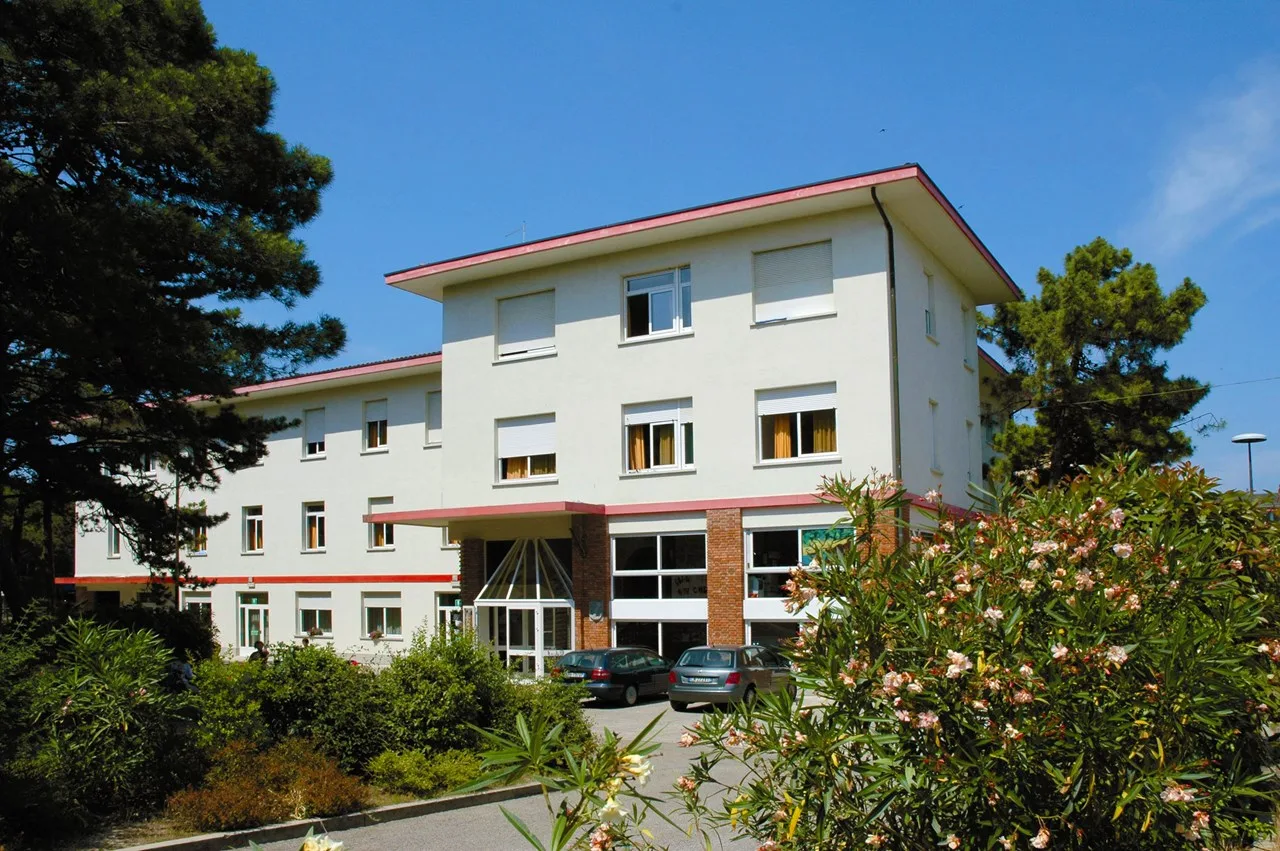 Edificio bianco con dettagli rossi e vegetazione fiorita