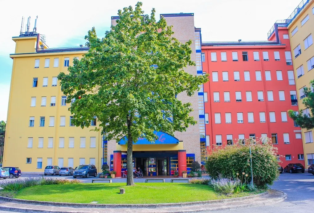 Facciata colorata gialla e rossa dell'edificio con albero all'ingresso