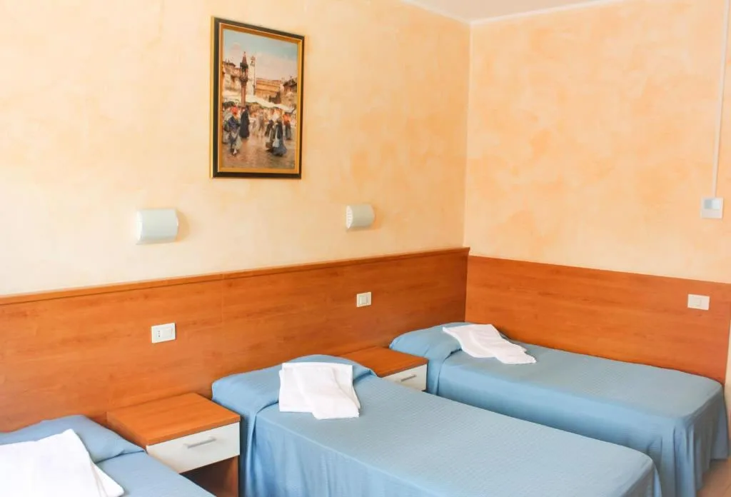 Camera con tre letti singoli, testiera in legno e quadro decorativo