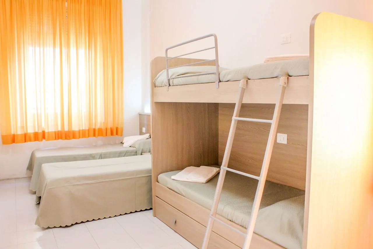 Camera con letto a castello e letto singolo con tende arancioni