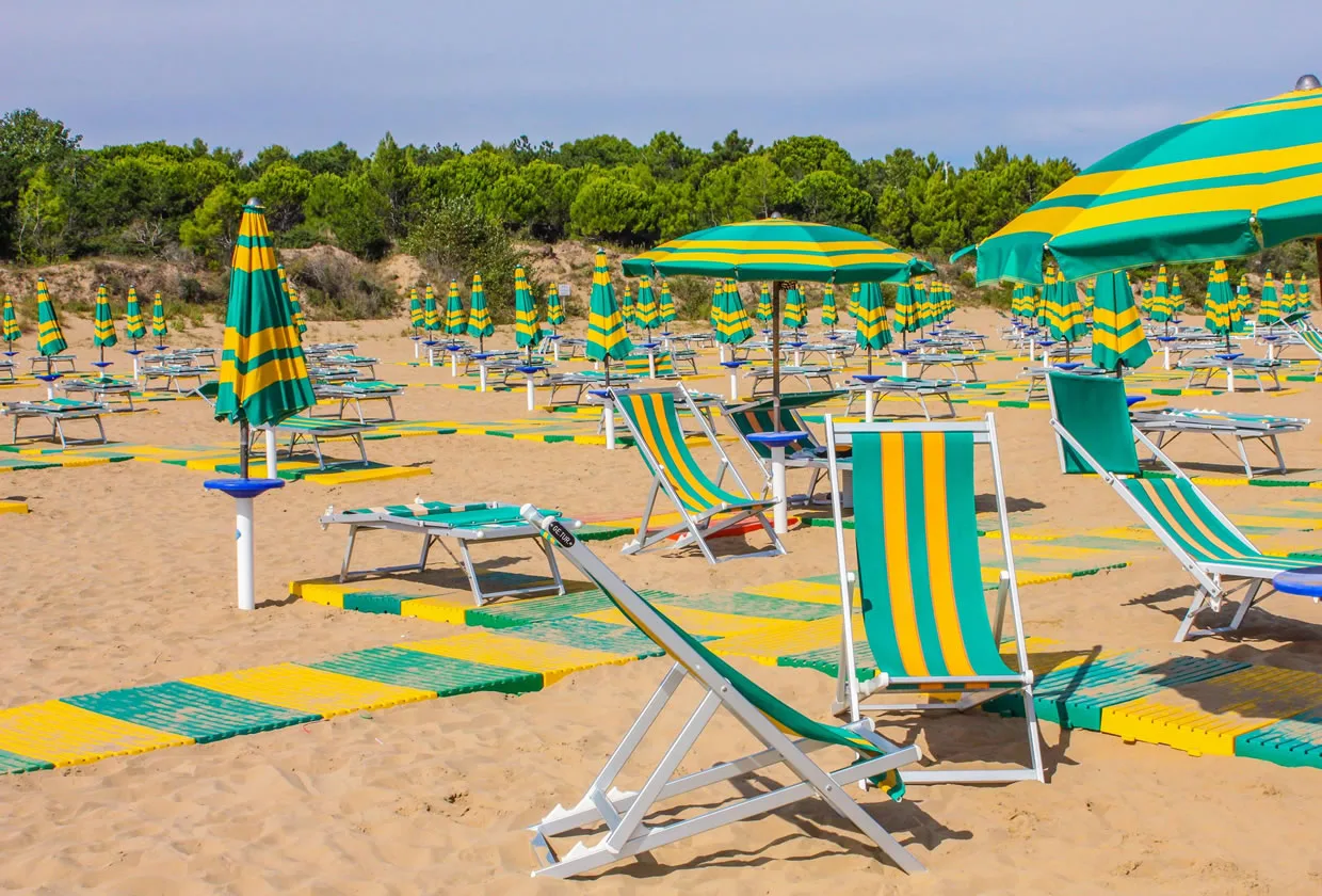 Spiaggia con ombrelloni e sdraio a righe verdi e gialle sulla sabbia