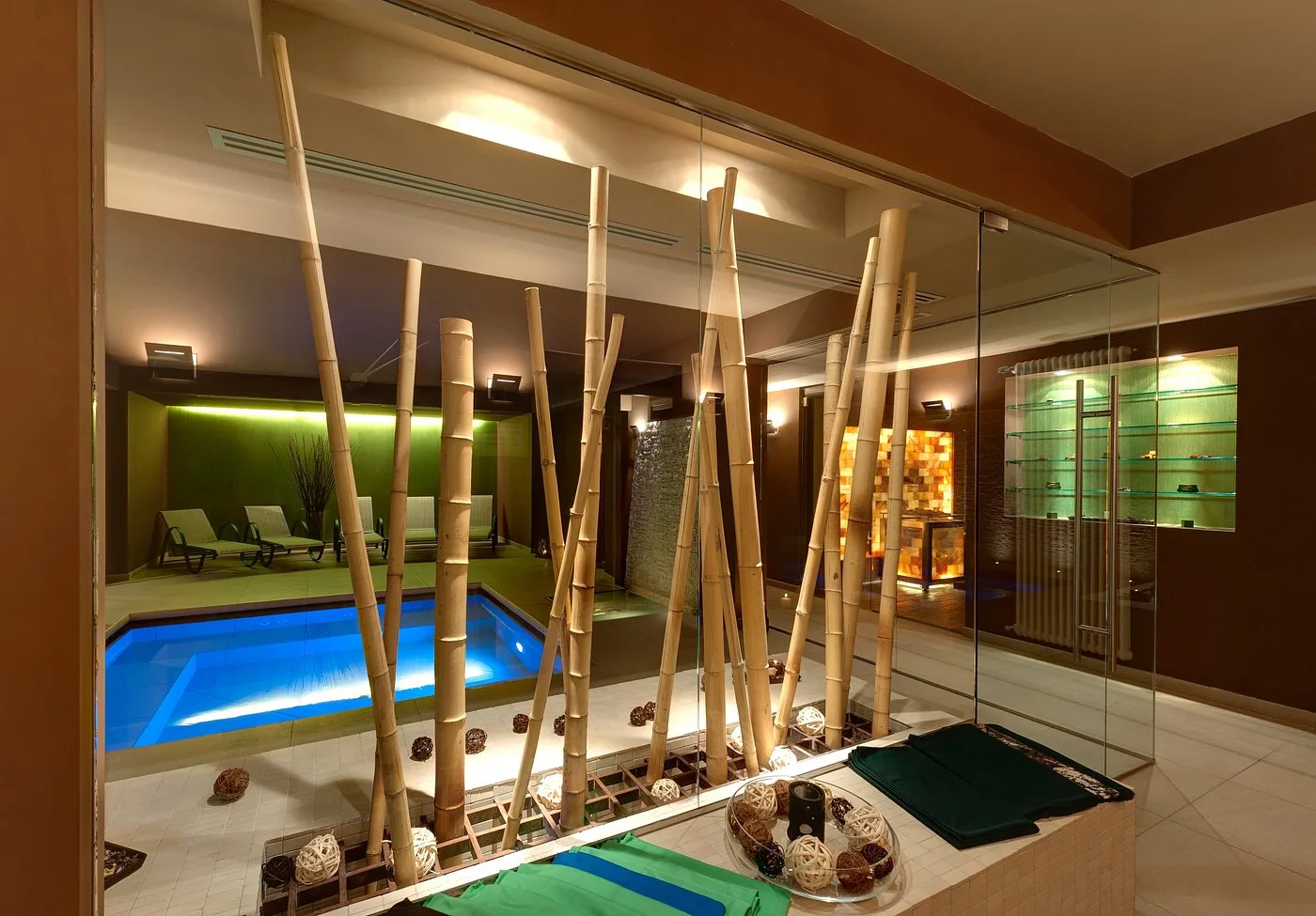 Zona benessere con decorazioni in bambù, piscina interna illuminata e vetrata