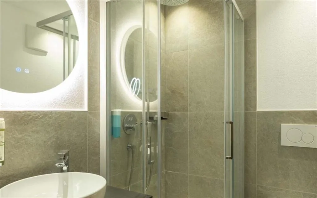 Dettaglio del bagno con specchio circolare retroilluminato e box doccia