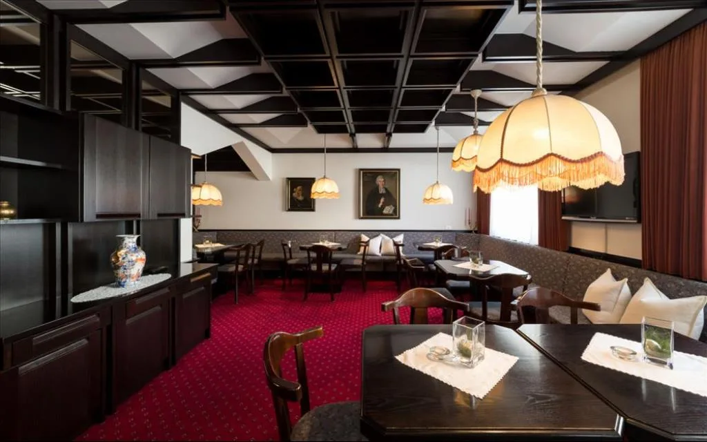 Sala interna con soffitto a cassettoni, tappeto rosso e lampade classiche
