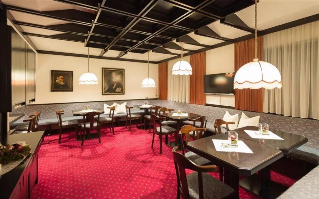 Sala da pranzo elegante con tavoli, panche e ritratti alle pareti