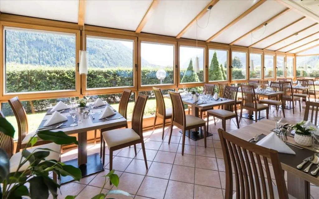 Veranda ristorante luminosa con grandi vetrate e vista sui monti