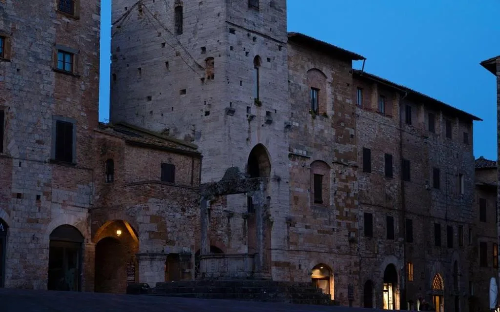 Piazza medievale di San Gimignano con torri e palazzi in pietra al crepuscolo