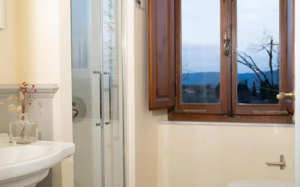 Bagno con lavabo, doccia e finestra con vista sulle colline