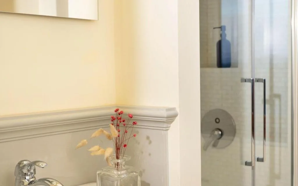 Dettaglio del bagno con lavabo, specchio e doccia con vetro