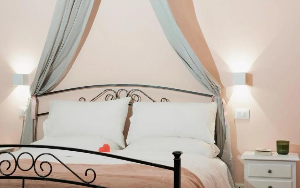 Letto matrimoniale in ferro battuto con baldacchino e cuscini bianchi