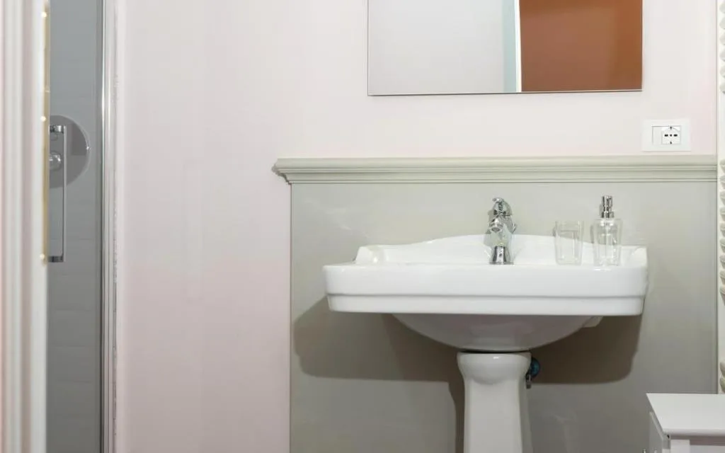 Bagno con lavabo bianco, specchio e box doccia in vetro