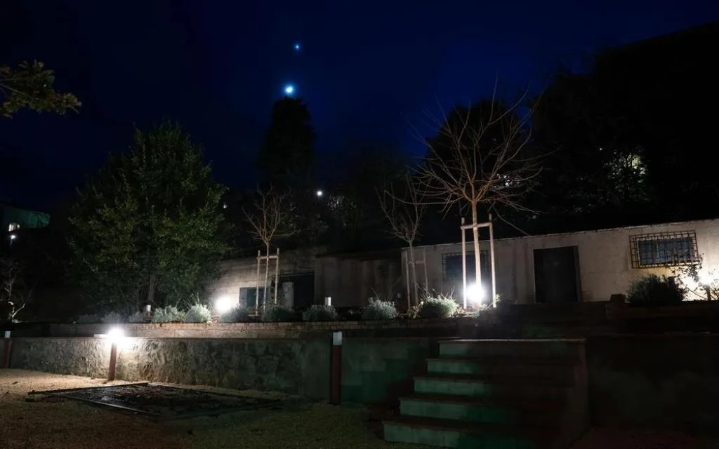 Giardino illuminato di notte con muretti, scale e alberi