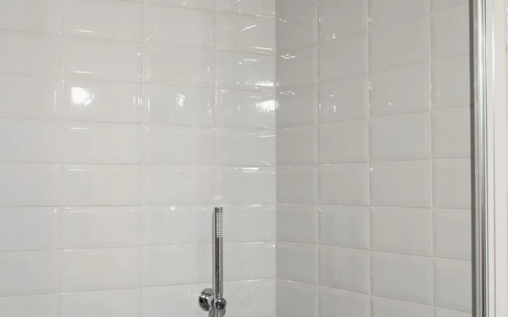 Doccia con rivestimento in piastrelle bianche e soffione a mano