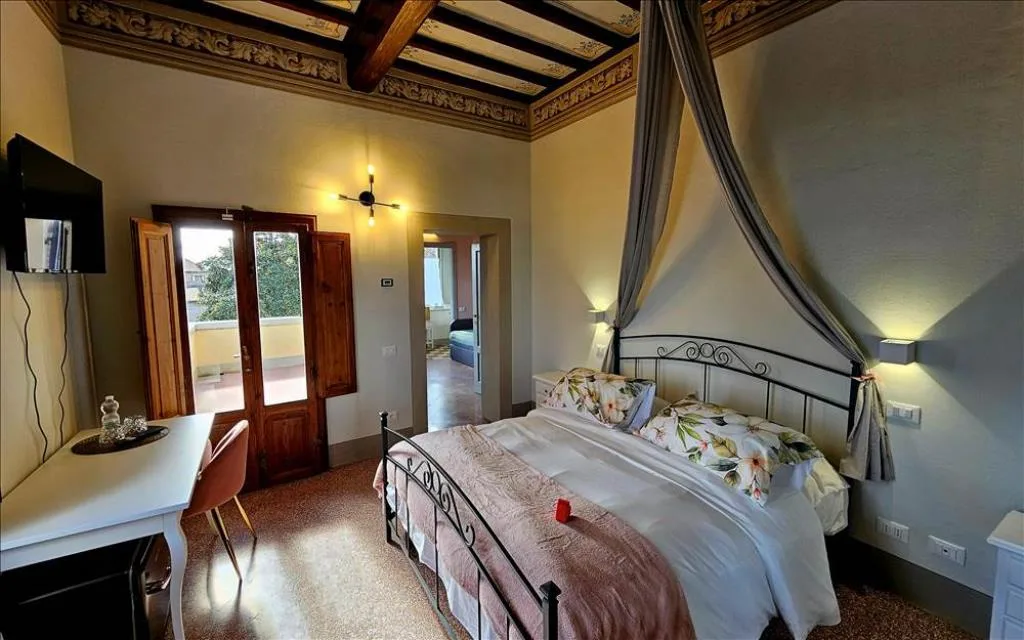 Camera elegante con soffitto affrescato a travi, letto con baldacchino e scrivania