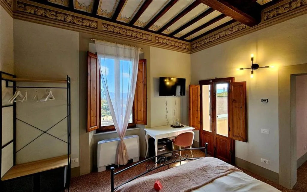 Camera storica con soffitto decorato a travi e finestra con imposte in legno
