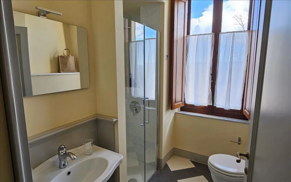Bagno luminoso con lavabo, box doccia e finestra con vista