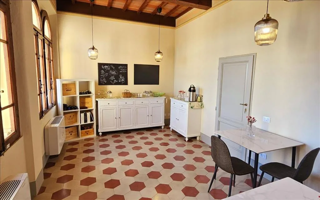 Sala colazione con credenze bianche, tavolo e pavimento a esagoni colorati