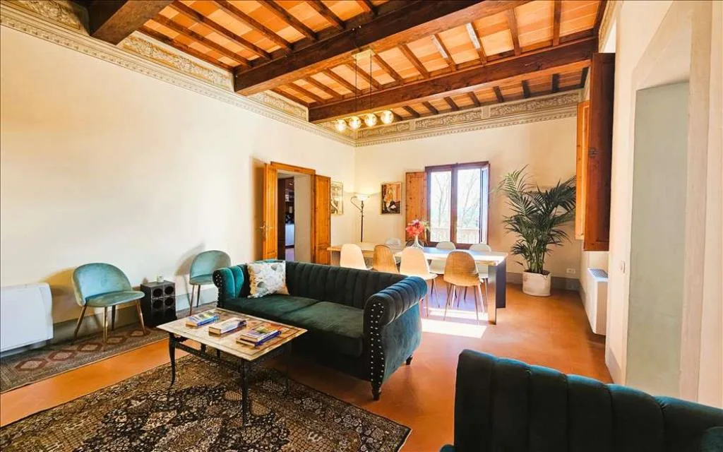 Ampio soggiorno con soffitto a travi, divani verdi e zona pranzo