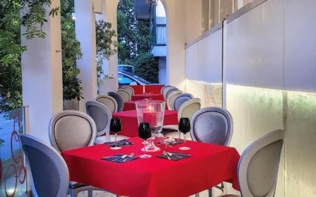 Tavoli del ristorante all'aperto sotto il portico con tovaglie rosse, calici e candele