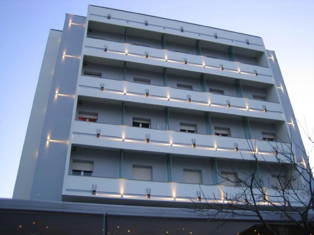 Facciata laterale dell'hotel con balconi e illuminazione architettonica al crepuscolo