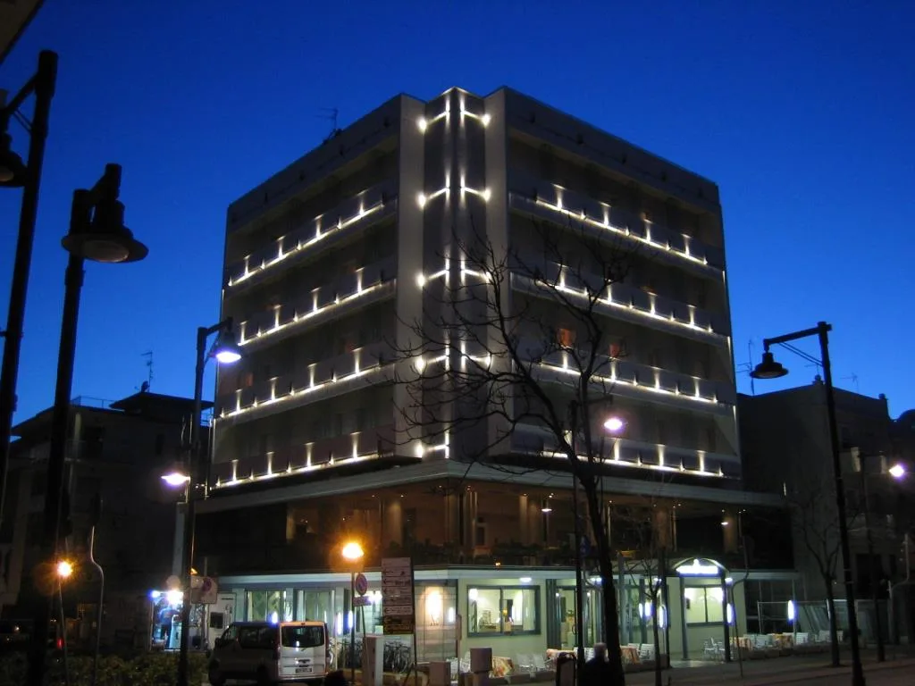 Esterno dell'hotel illuminato di notte con insegne e vetrate al piano terra