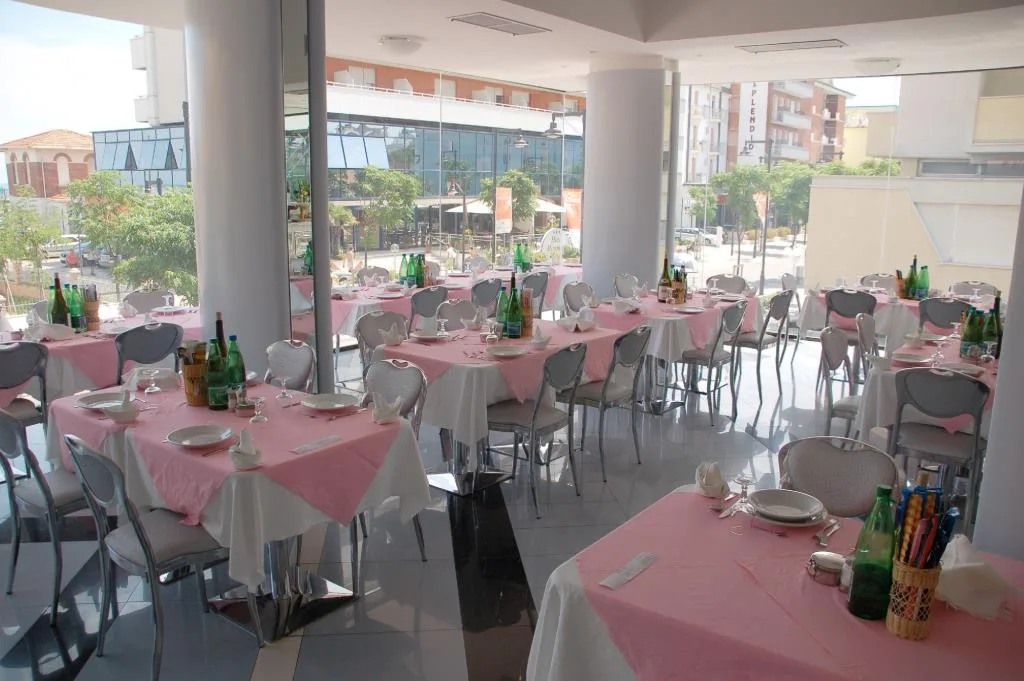 Sala ristorante luminosa con tavoli apparecchiati con tovaglie rosa e ampie vetrate