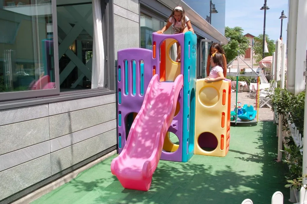 Area giochi esterna per bambini con scivolo colorato e bimbi che giocano