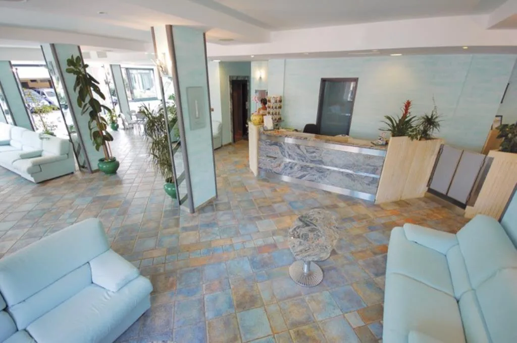 Reception e hall dell'hotel con bancone in marmo, divani chiari e pavimento in cotto colorato