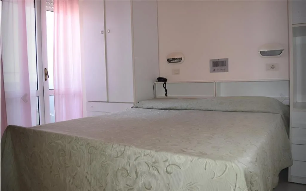 Camera matrimoniale con letto, tende rosa e arredi bianchi