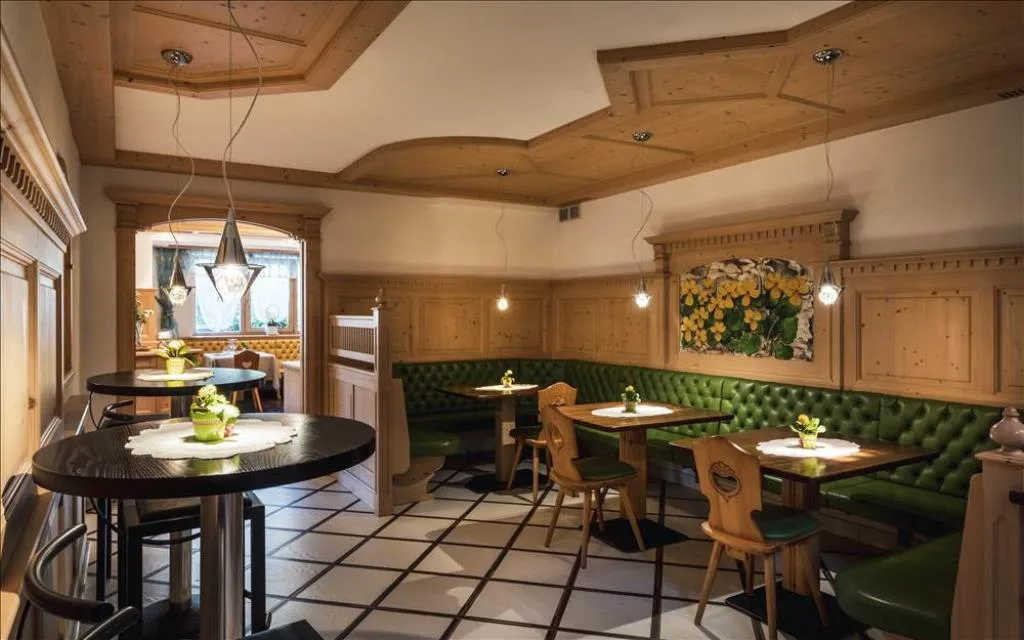 Sala da pranzo con arredi in legno, panche verdi e soffitto decorato