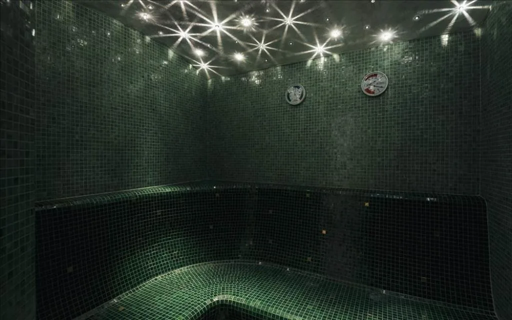 Bagno turco con mosaico verde scuro e illuminazione a stella sul soffitto