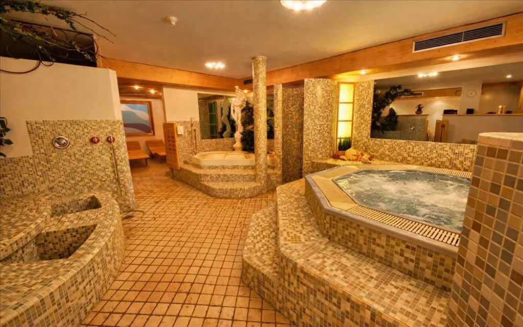 Area spa con vasca idromassaggio e mosaici a tessere sui toni beige