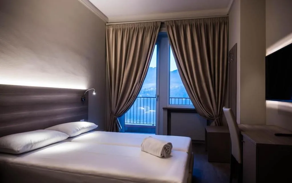 Camera matrimoniale moderna con letto, scrivania e balcone con vista serale