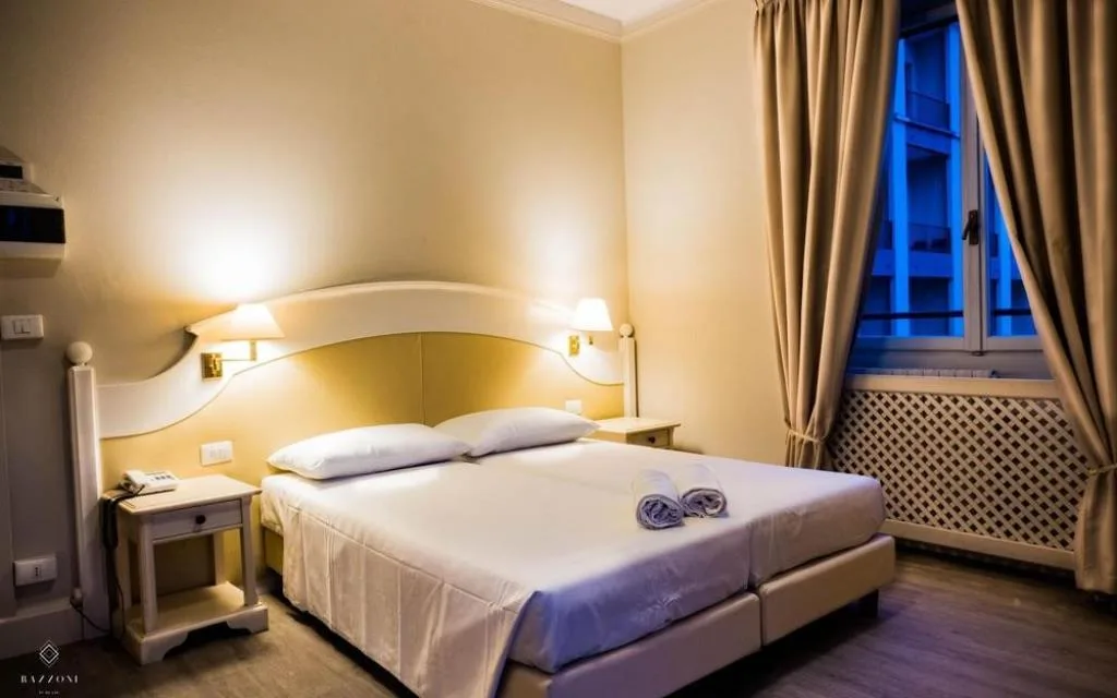 Camera d'albergo tradizionale con letto matrimoniale, comodini e finestra