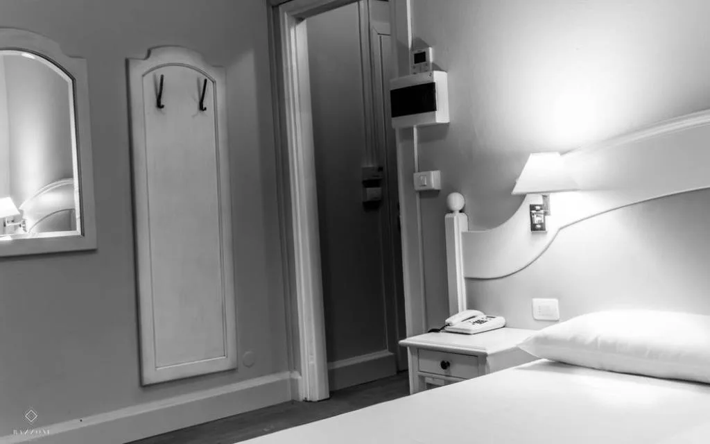 Dettaglio di camera con comodino, telefono e ingresso in bianco e nero
