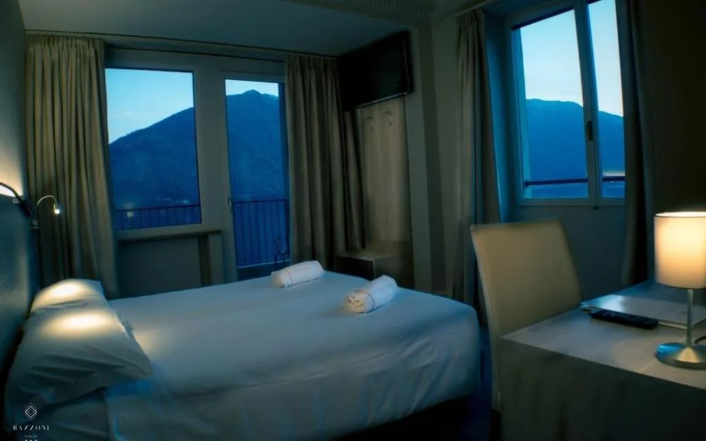Camera con letto matrimoniale illuminata in tonalità blu con finestre sul lago