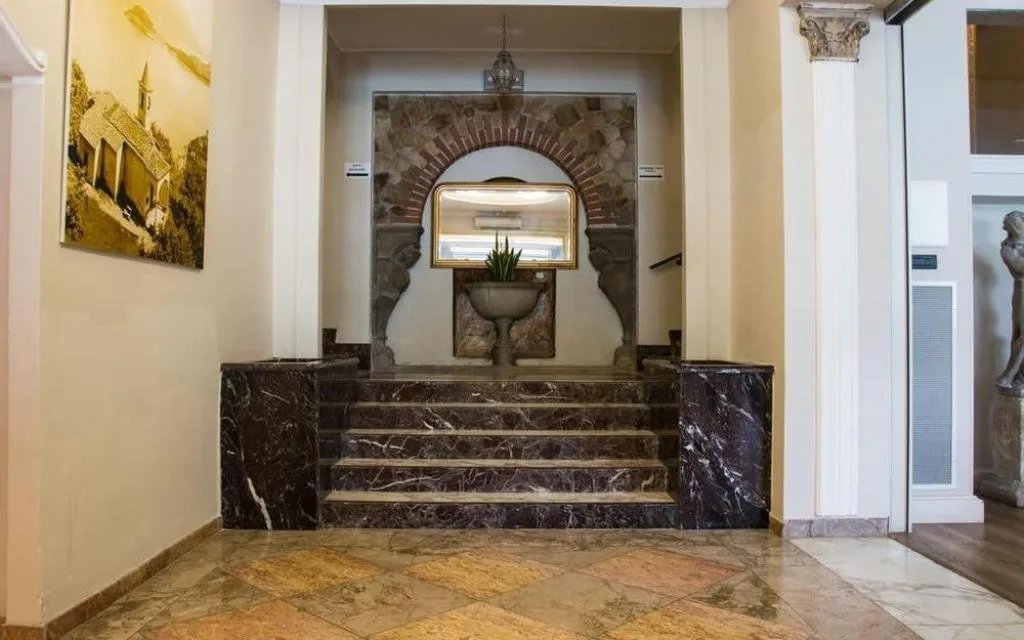 Ingresso interno con scala in marmo, specchio e decorazioni in pietra