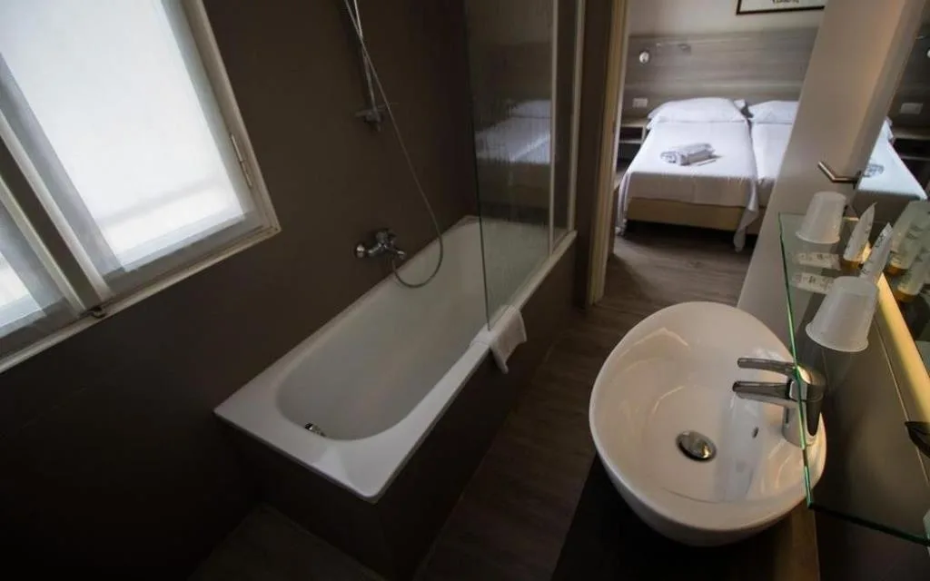 Bagno moderno della camera con vasca, lavabo tondo e vista sul letto