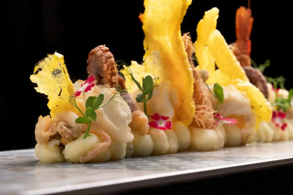 Piatto creativo di frittura di pesce e crostacei con fiori commestibili