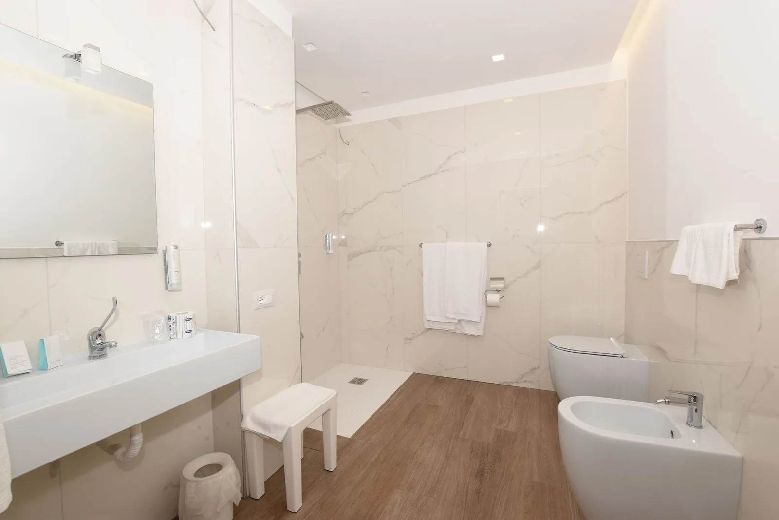 Bagno moderno con doccia a pioggia, lavabo, wc e bidet in marmo bianco
