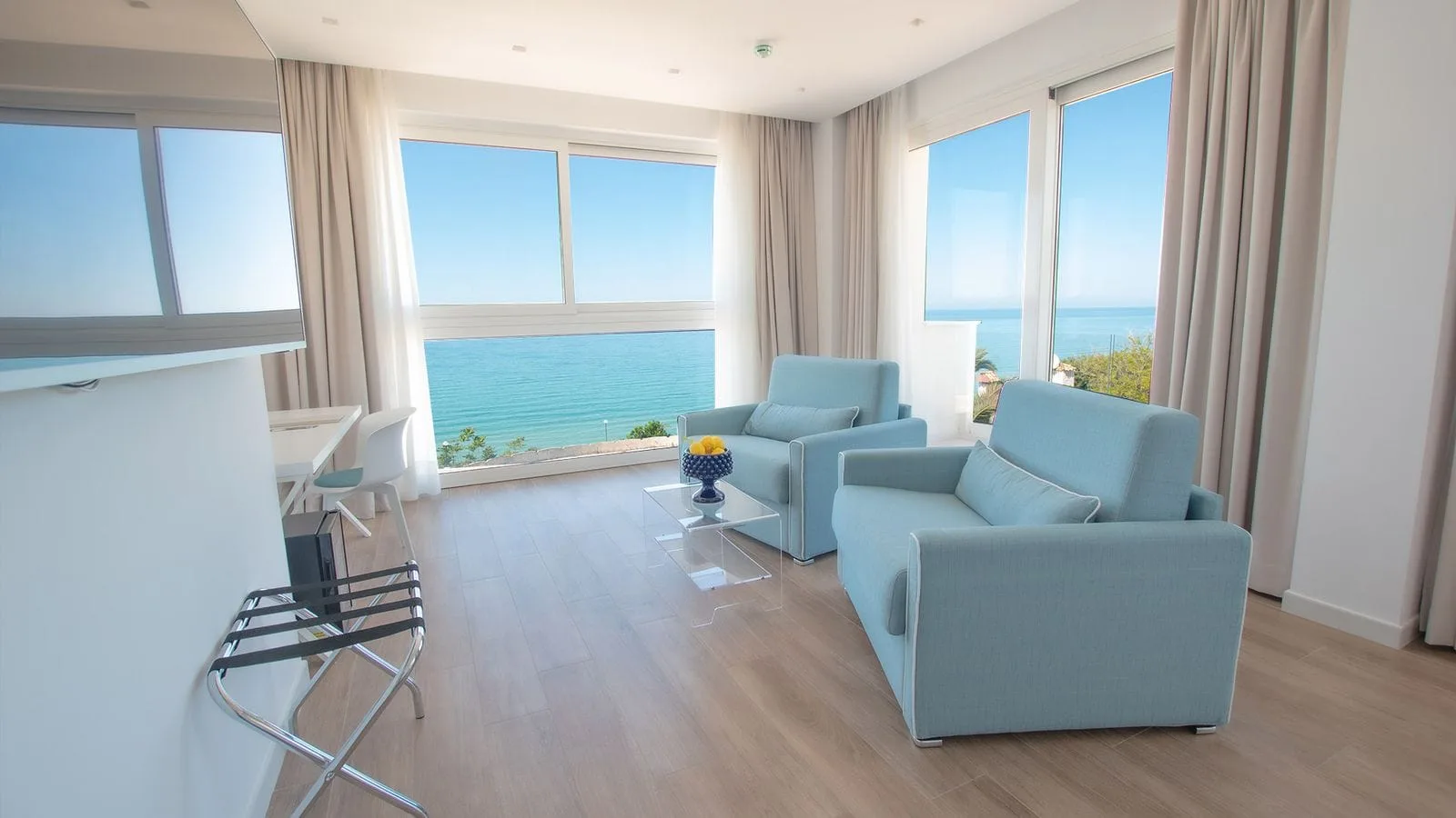 Soggiorno della suite con poltrone azzurre e vista panoramica sul mare