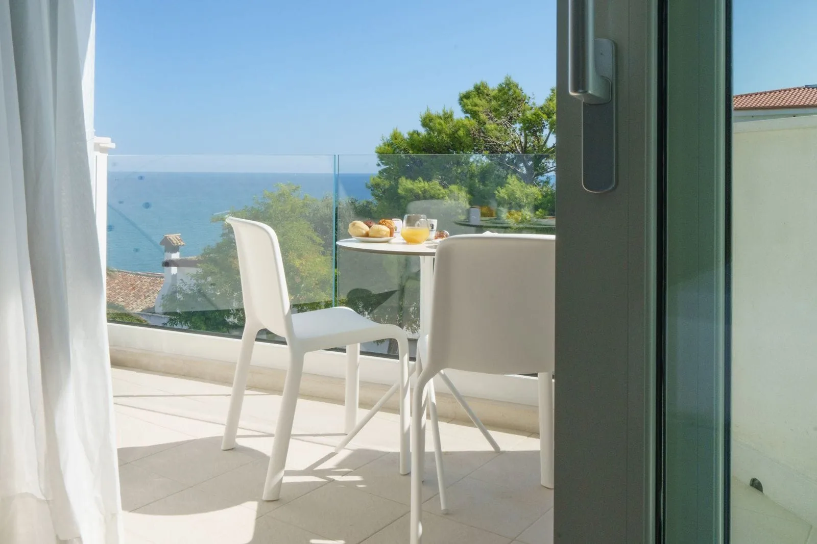 Balcone con tavolino, colazione e vista sul mare e la vegetazione