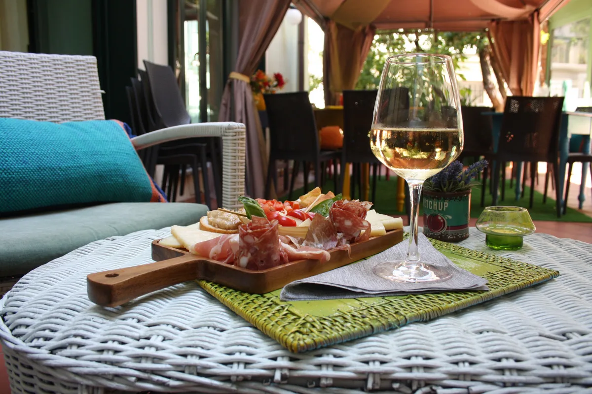 Tagliere di salumi e formaggi con calice di vino bianco all'aperto