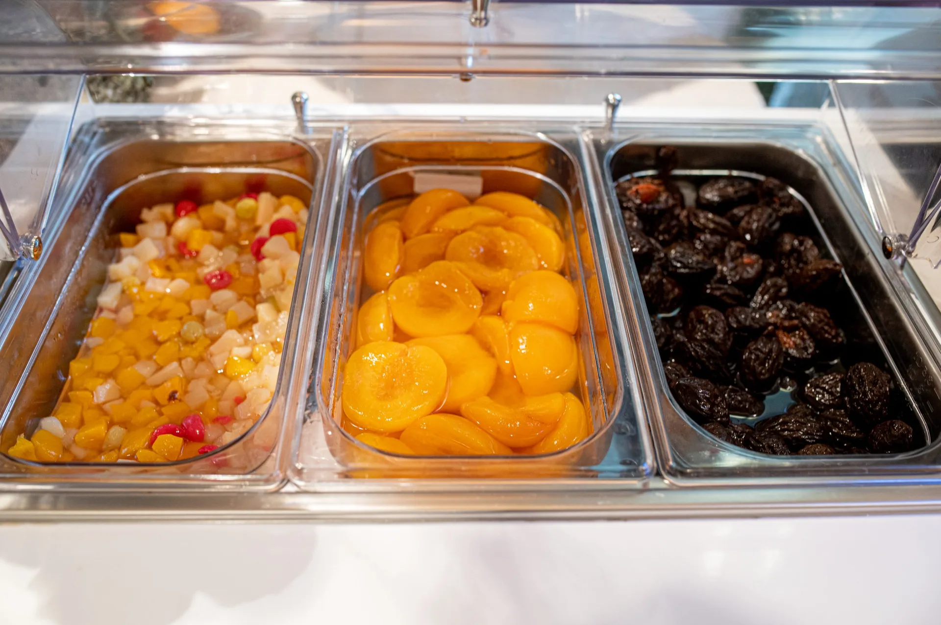 Buffet con frutta sciroppata e frutta secca in contenitori refrigerati